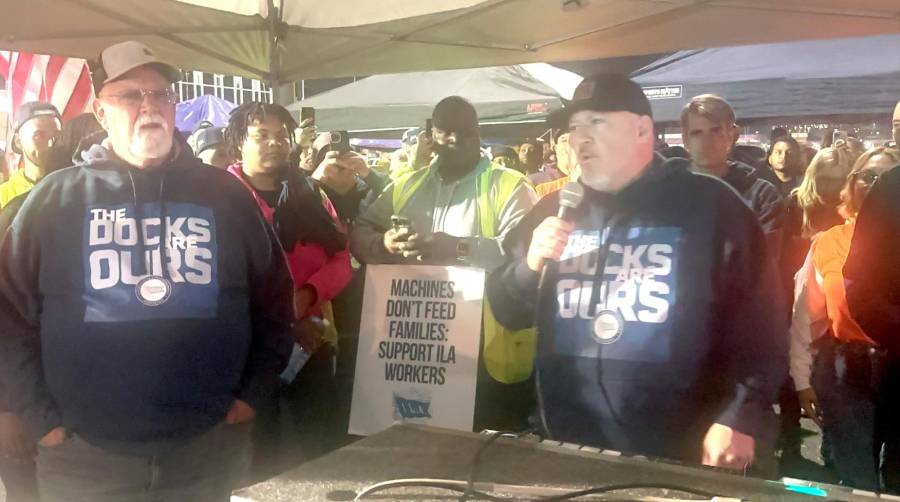 “Los muelles son nuestros”, se lee en las sudaderas de los líderes de la ILA, mientras uno de sus miembros porta un cartel con la leyenda: “Las máquinas no alimentan a las familias. Apoya a los trabajadores de la ILA”. Detrás, a la derecha, puede verse a Jordi Aragunde, coordinador general de la International Dockworkers Council (IDC).